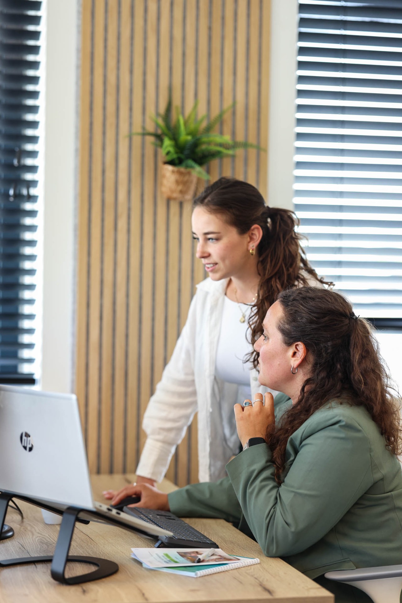 Twee adviseurs werken samen achter een laptop